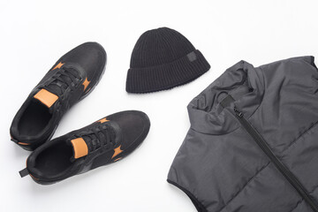 Men's sleeveless down jacket, sneakers and hat on a white background. Top view. Sportswear.