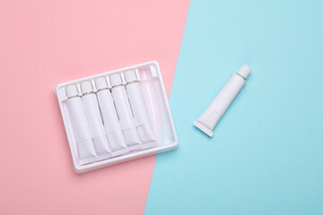 Set of white empty tubes of acrylic or oil paint for creativity on pink blue background. Template for design, mockup