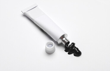 White empty tube of black acrylic or oil paint for creativity on white background. Template for design, mockup