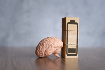 Closeup image of brain and wooden blocks with low energy battery icon. Exhausted, tired and burnout...