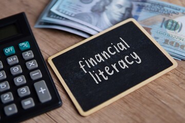 Top view image of piggy bank, calculator and money with text FINANCIAL LITERACY.