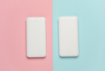 White power banks on pink blue background. External batteries for charging smartphone and other...