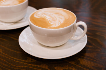 A cup of coffee on the table. Freshly brewed latte coffee on a brown wooden table.