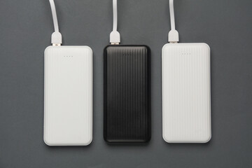 Power banks with cable on dark gray background. External batteries for charging smartphone and...