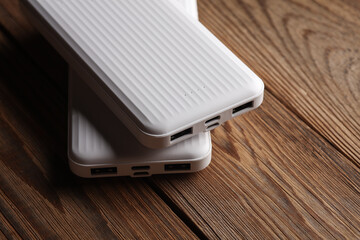 Power banks on wooden table. External batteries for charging smartphone and other gadgets.