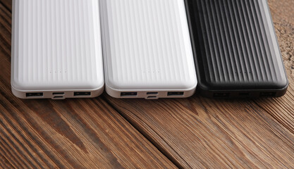 Power banks on wooden table. External batteries for charging smartphone and other gadgets.