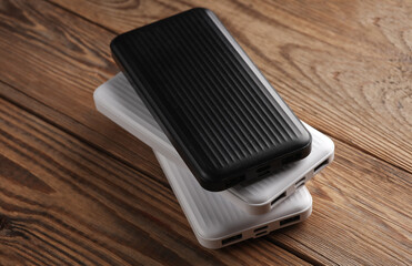 Power banks on wooden table. External batteries for charging smartphone and other gadgets.