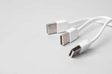 Three white USB cables on a gray background