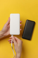 Hands holding white power bank on yellow background