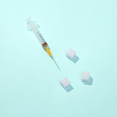 Syringe with sugar cubes on a bright blue background. Diabetes. Minimal medicine concept