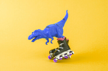 Toy dinosaur tyrannosaurus rex with roller skates on a yellow background. Minimalism creative layout
