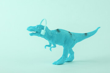 Toy dinosaur tyrannosaurus rex with headphones on blue background. Minimalism creative layout