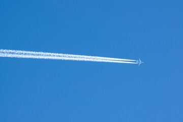 A white footprint on the blue sky, a footprint from the flight of a passenger plane.