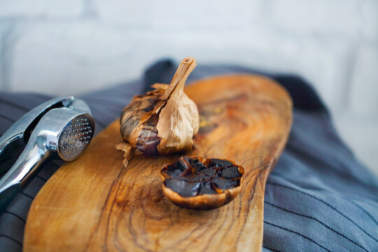 Black garlic bulbs and cloves on wooden background
