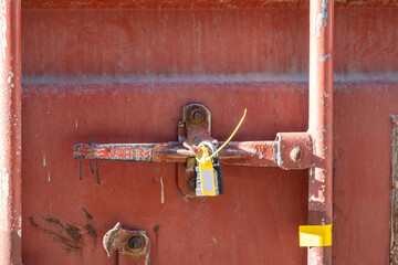 Closed door of a shipping container with a lock and a plastic clip.
