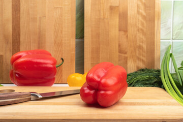 Close-up of a red sweet pepper and a kitchen knife on a cutting board.