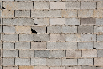 The texture of a brick wall with flaws. A gray wall of square cement blocks.