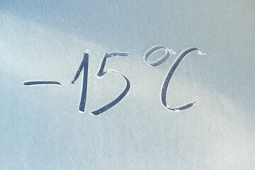 The inscription on the frozen glass is -15 degrees. The concept of lowering the temperature.