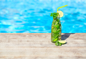 Mojito cocktail at the edge of a resort pool. Concept of luxury vacation