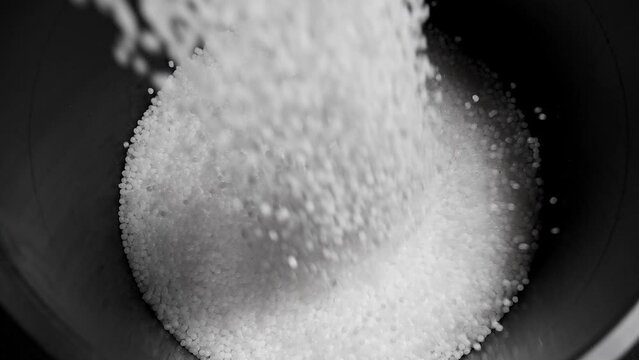 Filling the tank with plastic granules. The process of producing parts from polyethylene compound. White granules are poured into a container.