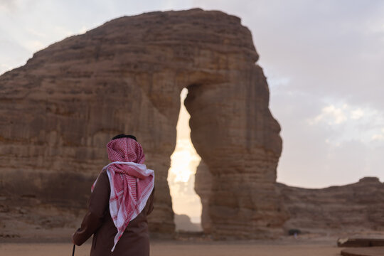 Man in desert looking at Al Ula most attractive place known as Elephant Rock which is situated in Saudi Arabia. One among the famous tourist attraction in Saudi Arabia.