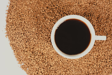 A cup of hot instant coffee on a background of freeze-dried granules