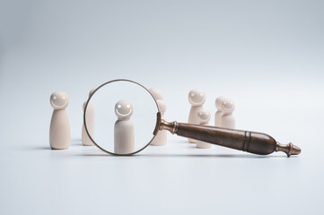 Magnifying glass focus wood doll which is among crowd for human development recruitment leadership...