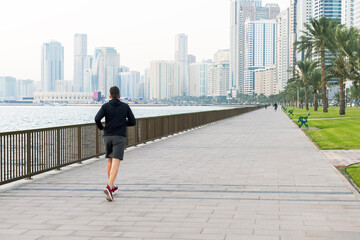 Naklejka premium Urban man runner running on waterfront in city.