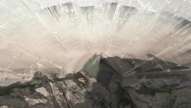 Tilted downward aerial view of a huge old dam with water leaks