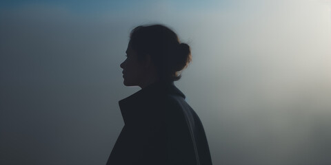 Profile of a young woman, backlit by a soft glow, creating a sense of calm introspection