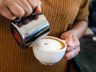 Barista pouring milk into coffee making a cappuccino. Barista making cappuccino,Professional bartender preparing coffee drink