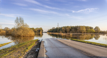 The field and road are flooded with water, natural disaster, spring flood. A road in a rural area...
