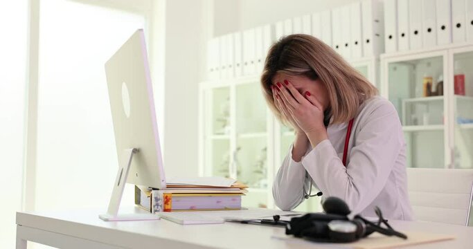 Frustrated nurse works on computer in clinic. Unhappy crazy female doctor using computer in hospital confusing operating problem or device spam