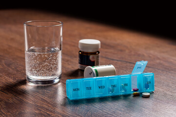 Pill organizer with variety of pills and supplement. Weekly Pill Organizer on the table.