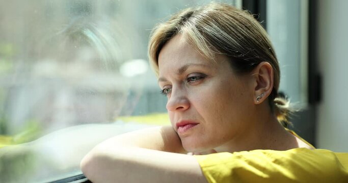 Sad frustrated young woman thinking and looking out window. Personal troubles and partings is going through difficult life situation