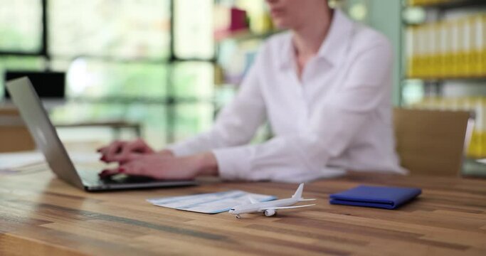 Woman working on laptop computer looking for flight using an online service. Manager secretary in office booking round trip plane ticket on website