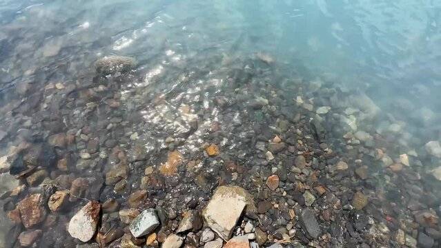 Crystal clear and clean water of the lake with stones in the background