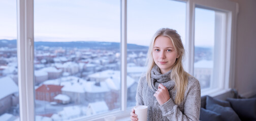 primo piano di giovane donna nordica in luminoso ambiente abitazione, ufficio con vista di panorama invernale - obrazy, fototapety, plakaty