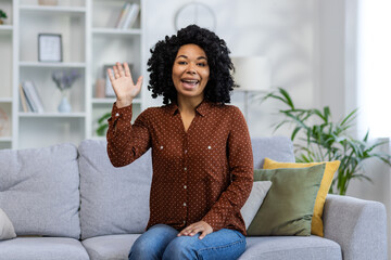 Portrait of a smiling young African American woman sitting on the couch at home in front of the...