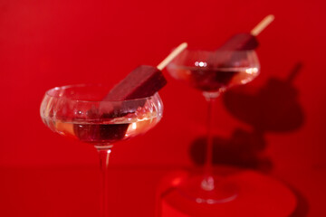 Two glasses of champagne and choclate ice cream on the podium. Stylish alcohol cocktail on red background.