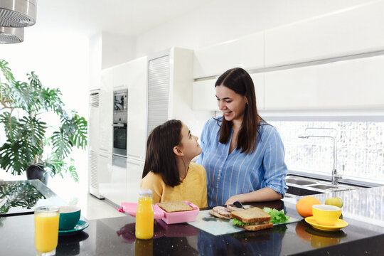 Cheerful Ethnic Mother Making Healthy Lunch Box With Healthy Food For Her Little Daughter