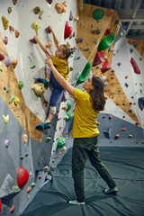 Little girl, child training with instructor, practicing bouldering activity, techniques. Little...