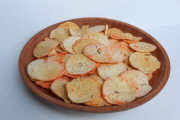 Opak is crisp made from cassava, shaped into a flat round shape. Snack from Indonesia. On a wooden plate, isolated on white background