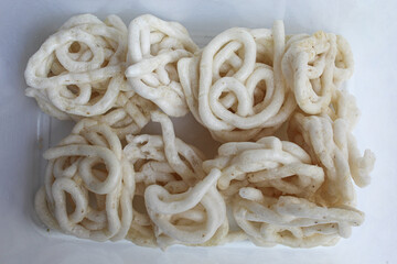 Kerupuk Putih Kampung, flour crackers or food condiment from Indonesia, in a plastic transparent box Isolated on white background