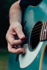 Close up of man's hand playing acoustic guitar. Musical instrument for recreation or hobby passion...