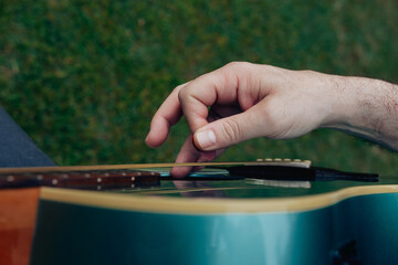 Close up of man's hand playing acoustic guitar. Musical instrument for recreation or hobby passion...