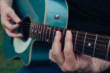 Fototapeta na wymiar Close up of man's hands playing acoustic guitar. Musical instrument for recreation or hobby passion concept