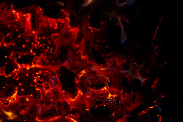 Hot burning coals with sparks on a black background
