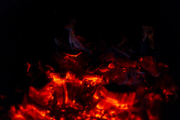 Beautiful coals with fire burning in the night. Coals on a black background