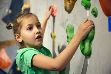 L:ittle girl, child attending bouldering course, training, climbing wall indoors. Sport education. Concept of bouldering, sport climbing, hobby and active lifestyle, school, training course © master1305